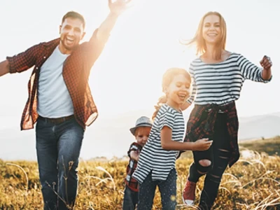 Fotografía de una mujer, un hombre, una niña y un niño. Los cuatro sonríen mientras corren hacia la cámara.