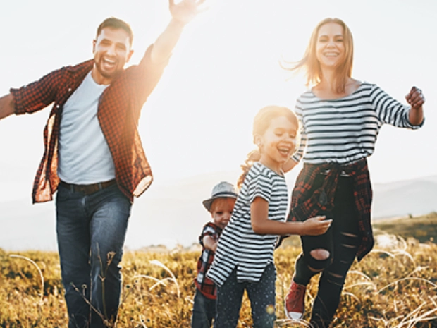 Fotografía de una mujer, un hombre, una niña y un niño. Los cuatro sonríen mientras corren hacia la cámara.