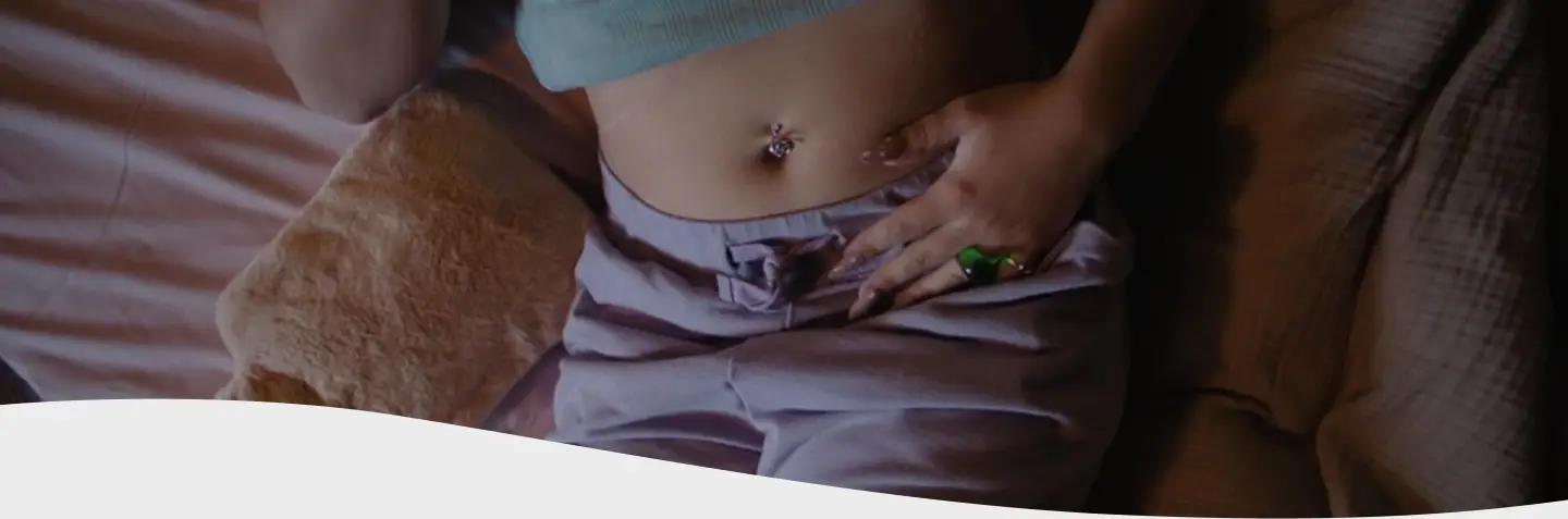 Mujer encorvada con cara de dolor sosteniéndose la panza