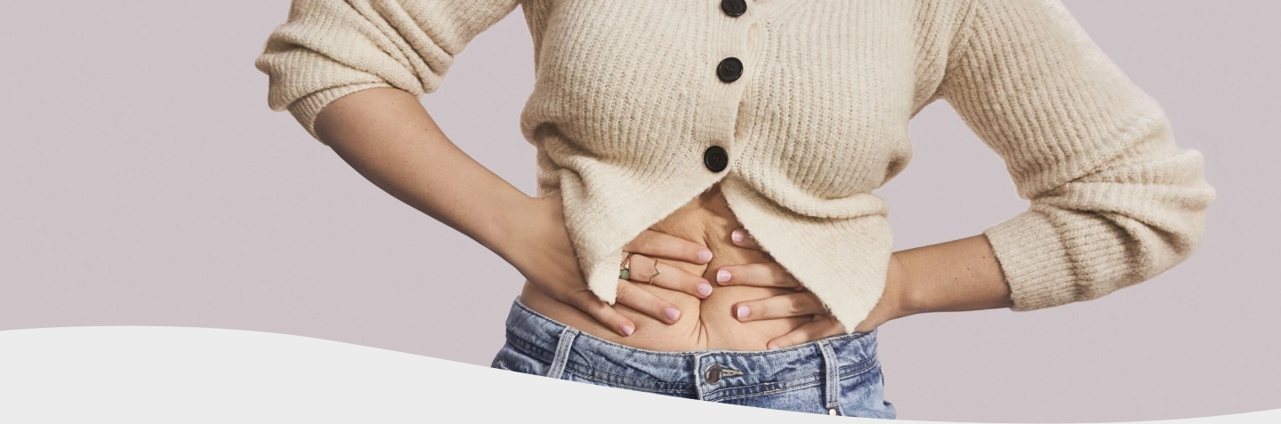 Hombre con chomba con cara de dolor mientras sostiene una hamburguesa y unas papas fritas