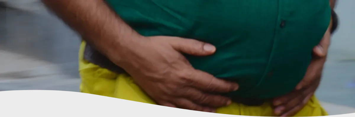 Hombre con chomba con cara de dolor mientras sostiene una hamburguesa y unas papas fritas