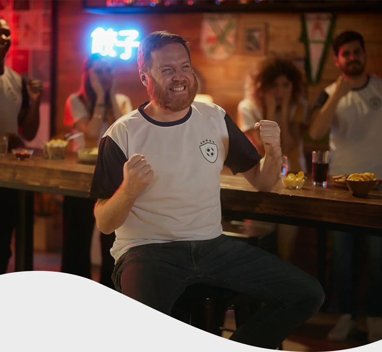 Hombre con remera de futbol festejando en un bar