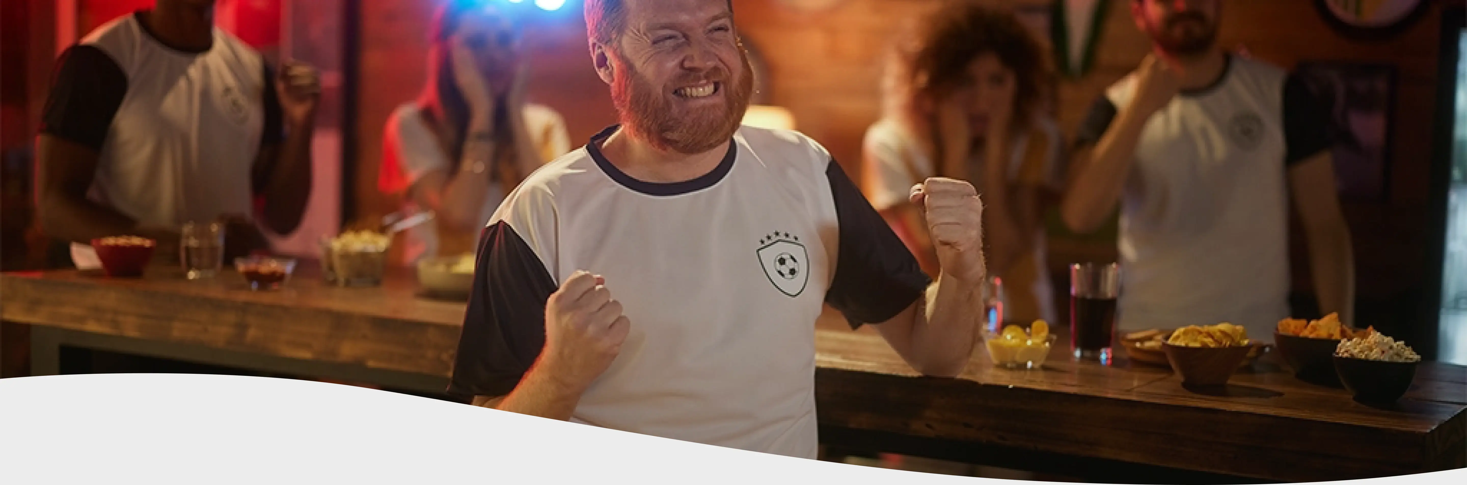 Hombre con remera de futbol festejando en un bar