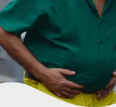 Hombre con chomba con cara de dolor mientras sostiene una hamburguesa y unas papas fritas