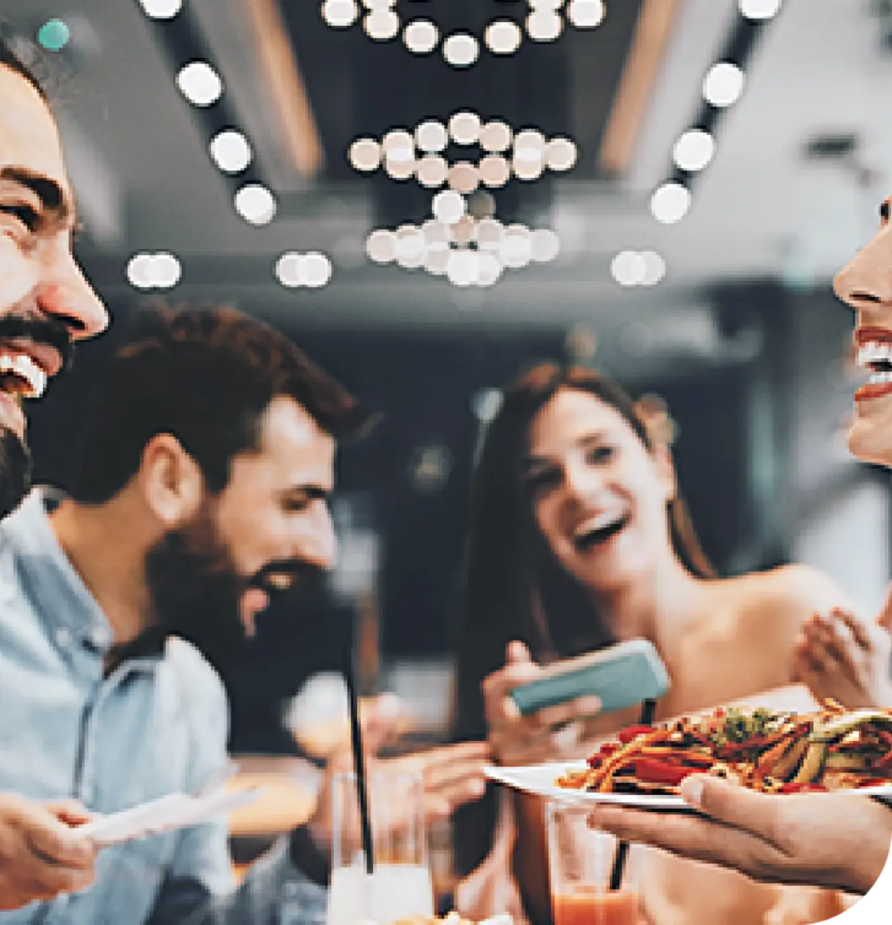 Fotografía de dos mujeres y dos hombres sonrientes, compartiendo una comida en una mesa.