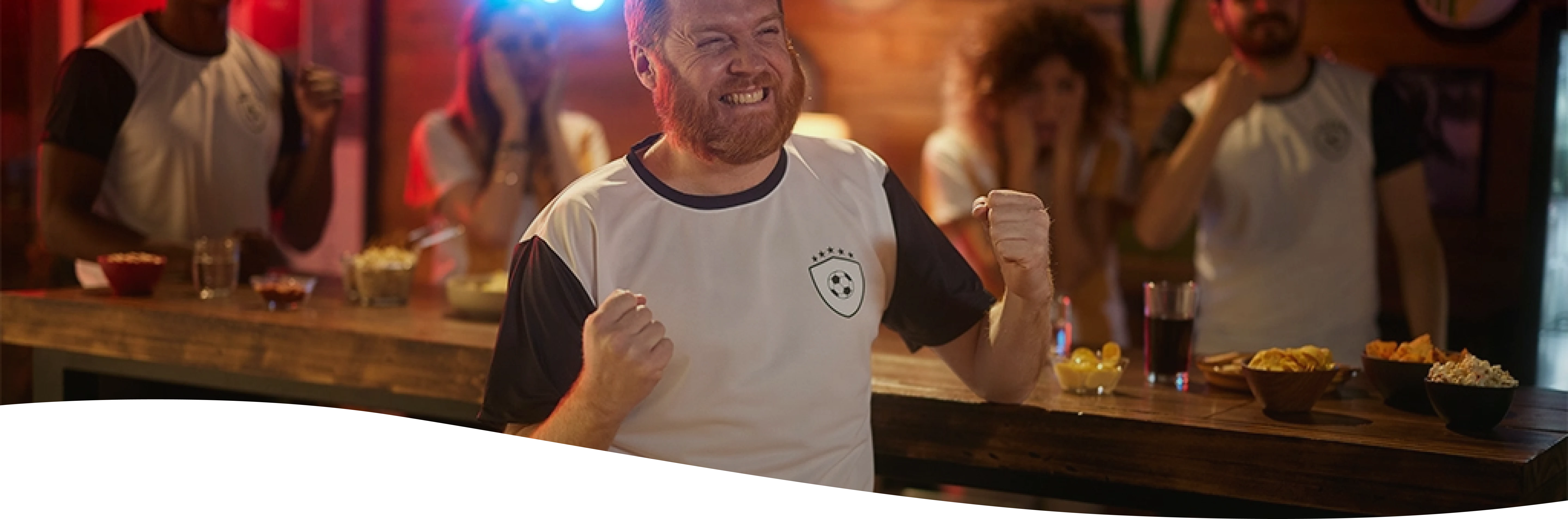 Hombre con remera de futbol festejando en un bar